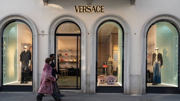 Luxury fashion retailers are accelerating store closures as slowing demand, economic uncertainty, and shifting consumer spending force even the industry's biggest names to rethink their global footprints.Over the past year, several luxury companies have announced plans to shrink their retail networks as they prioritize stronger-performing locations, streamline operations, and invest in long-term growth rather than maintaining expansive store portfolios.<a href="https://www.thestreet.com/retail/luxury-giant-to-close-200-stores-after-sales-drop-kering-retail">Kering closed 133 stores</a> across its brands in 2025 and plans to shutter an additional 100 locations, with further reductions under review. The French multinational luxury goods group owns some of the most recognizable luxury houses, including Gucci, Saint Laurent, Bottega Veneta, Balenciaga, and Alexander McQueen.Ferragamo also expects to close roughly <a href="https://www.businessoffashion.com/articles/luxury/is-ferragamos-turnaround-finally-on-track/">70 stores</a> between 2025 and 2026, while <a href="https://www.thestreet.com/retail/170-year-old-luxury-fashion-retailer-quietly-closes-21-stores-burberry">Burberry shuttered 21 locations</a> during fiscal 2026.Industry analysts do not expect a rapid recovery.According to the <a href="https://www.mckinsey.com/industries/retail/our-insights/state-of-fashion">McKinsey & Company State of Fashion 2026 Report</a>, the global fashion industry is projected to grow only in the low single digits in 2026, as macroeconomic <a href="https://www.thestreet.com/dictionary/v/volatility">volatility</a>, tariff pressures, and weaker consumer sentiment continue to weigh on demand, particularly in the U.S.Now, another iconic luxury company is the latest to reduce its retail footprint while accelerating a broader brand transformation.Founded in 1913, the Prada Group is a Milan-based global luxury fashion company that owns Prada, Miu Miu, Versace, Church's, Car Shoe, Marchesi 1824, and Luna Rossa.The Prada Group confirms Versace store closuresThe Prada Group has confirmed that Versace will undergo additional <a href="https://www.thestreet.com/retail/ikea-closing-stores-small-format-plan-order-pick-up-in-us">store closures</a> in 2026 and 2027 despite performing in line with company expectations during the first half of the year, according to the company's <a href="https://finance.yahoo.com/quote/PRP.F/earnings/PRP.F-Q2-2026-earnings_call-550263.html">earnings call</a>.The planned closures are part of a broader effort to <a href="https://www.thestreet.com/retail/global-retailer-inditex-zara-closes-106-stores">eliminate non-strategic locations</a>, improve retail execution, and position the brand for its next phase of growth following Prada's acquisition of Versace."Retail execution continued to be a key area of focus alongside the rationalization of the network with selected closures of non-strategic stores," said Prada Group CMO and Head of Corporate Social Responsibility Lorenzo Bertelli during the earnings call.The company has already closed 10 Versace stores since the end of 2025 and plans to shutter approximately 10 more locations while relocating select boutiques to <a href="https://www.thestreet.com/retail/hm-79-year-old-fast-fashion-retailer-closes-128-stores">stronger markets</a>."Let's say we will have another slightly smaller network next year, from 2028, we will look at opportunities of better location," said Bertelli.As of June 30, 2026, the Prada Group operated 832 stores across more than 70 countries, according to its first-half 2026 <a href="https://www.pradagroup.com/content/dam/pradagroup/documents/investors/H1-2026/Prada-Group-H126-Press-release.pdf">earnings report</a>. Why the Prada Group is closing Versace storesThe closures come as the Prada Group continues integrating Versace after <a href="https://www.thestreet.com/retail/kering-exits-beauty-business-ends-gucci-partnership-coty">acquiring</a> the Italian fashion house from Capri Holdings in December 2025 in a cash deal valued at €1.25 billion (approximately $1.44 billion). The acquisition marked the <a href="https://www.thestreet.com/retail/luxury-fashion-icon-steps-down-after-nearly-three-decades">end of Donatella Versace's nearly 30-year leadership</a> of the brand. She stepped down as chief creative officer in April 2025, and Pieter Mulier officially became Versace's chief creative officer on July 1, 2026.Mulier's first collection, 'La Vacanza,' is scheduled to debut in May 2027, and the Prada Group expects all Versace stores to carry only his <a href="https://www.thestreet.com/entertainment/award-winning-music-star-unveils-zara-collection-bad-bunny-benito-antonio">collections</a> by the second half of 2028."We worked hard on many different things in these first six months, organization, synergies, costs, journey, commercial milestones. It's a long journey," said Prada Group CEO Andrea Guerra. "We need to fight. We need to get all the right opportunities and not burn any of them. We are all working on it. Even for the Versace brand, these first six months have been in line with our desires."The <a href="https://www.thestreet.com/retail/hm-79-year-old-fast-fashion-retailer-closes-128-stores">store closures</a> reflect the Prada Group's broader strategy to reshape Versace by concentrating investments in stronger retail locations and refining the brand's positioning under its new creative leadership.
The Prada Group confirms more Versace store closures through 2027.<a href="https://www.gettyimages.com/detail/news-photo/versace-luxury-fashion-store-on-via-montenapoleone-in-milan-news-photo/2187495928?slot=77">Francesca Volpi/Bloomberg via Getty Images</a>
The Prada Group posts continued growthDespite the changes at Versace, the Prada Group continued to deliver strong financial results.During the first half of fiscal 2026, the company reported a 16% year-over-year increase in net revenue, while <a href="https://www.thestreet.com/dictionary/r/retail-sales">retail sales</a> rose 12%.According to the company, Versace performed in line with expectations, as management focused on improving sales quality, strengthening retail execution, and beginning the brand's <a href="https://www.thestreet.com/retail/ulta-pacsun-partnership-after-target-split">creative repositioning</a> following Mulier's arrival.Versace accounted for approximately 10% of the Prada Group's first-half net revenue, totaling €305 million.Here's some of <a href="https://www.thestreet.com/author/fernanda-tronco">my previous coverage</a> of store closures:<strong><a href="https://www.thestreet.com/retail/tractor-supply-petsense-store-closures">88-year-old retailer closing 75 stores, slows expansion</a></strong><strong><a href="https://www.thestreet.com/retail/staples-closing-stores-2026">Former retail giant closes more stores</a></strong><strong><a href="https://www.thestreet.com/retail/garage-groupe-dynamite-after-closures-fashion-retailer-shifts-strategy">After years of store closures, fashion retailer shifts strategy</a></strong>"In a geopolitical and macroeconomic scenario that remained <a href="https://www.thestreet.com/retail/popular-retailer-flags-major-trend-that-could-save-luxury-fashion">turbulent</a>, we continued to execute with rigor," said Bertelli."Our commitment to the highest standards of product excellence, nurturing craftsmanship and creativity as non-negotiable pillars, allowed us to reach 22 quarters of uninterrupted organic growth. The environment is likely to remain volatile; we must stay nimble, innovate continuously, taking advantage of the strength of our manufacturing know-how, and continue to balance short-term discipline with <a href="https://www.thestreet.com/retail/glossier-after-closing-nearly-all-locations-gets-funding">long-term vision</a>."<strong><a href="https://www.thestreet.com/retail/nike-store-closures-2026">Related: Sportswear giant continues store closures nationwide</a></strong>